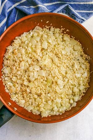 White rice and sautéed onions in a large copper skillet