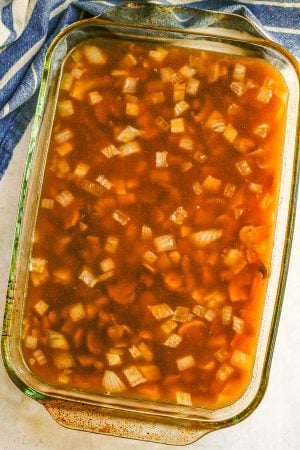 A glass baking dish with a mushroom rice mixture in beef broth