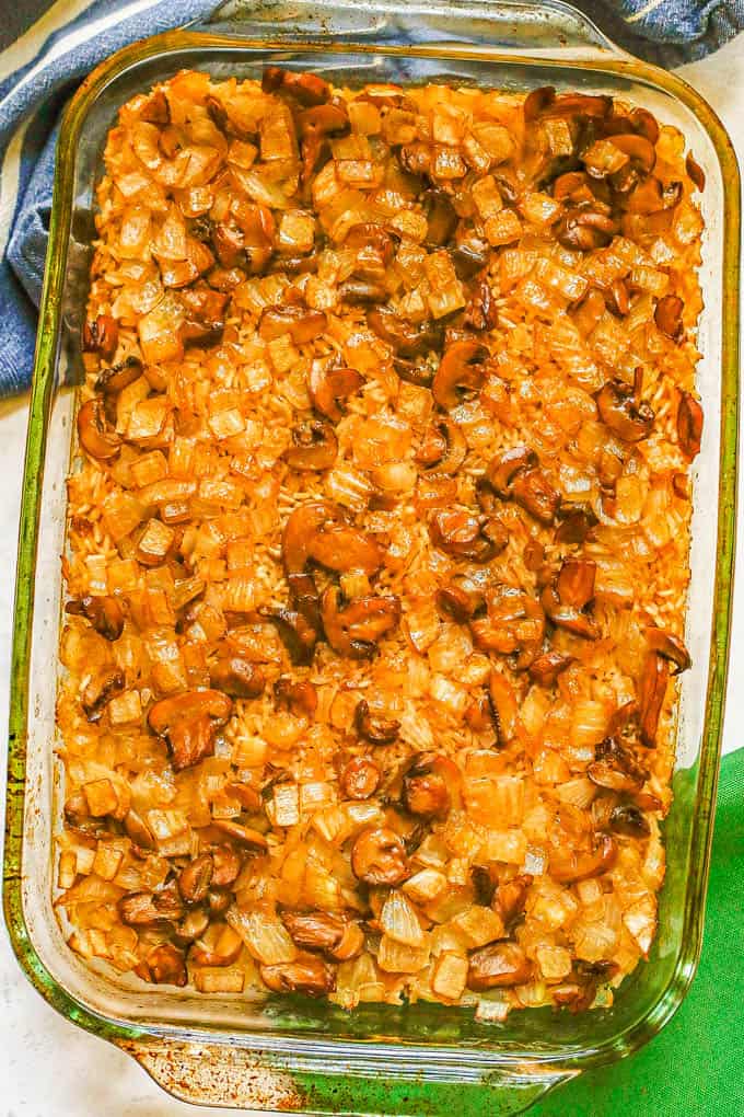 Baked mushroom rice casserole in a glass baking dish with green and blue napkins nearby