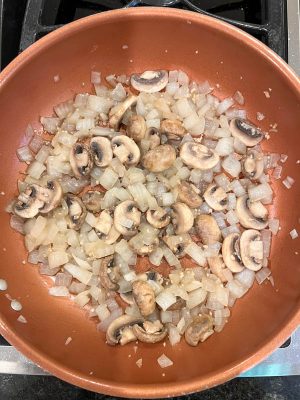 Sautéed onions and mushrooms in a copper pan