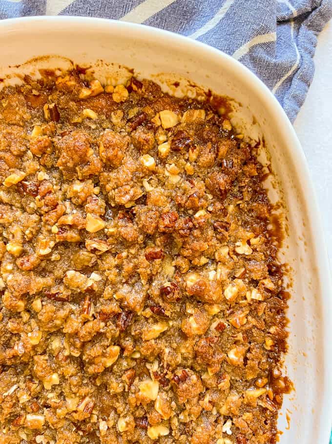 Close up of the nutty streusel topping on a baked sweet potato casserole in a white baking dish