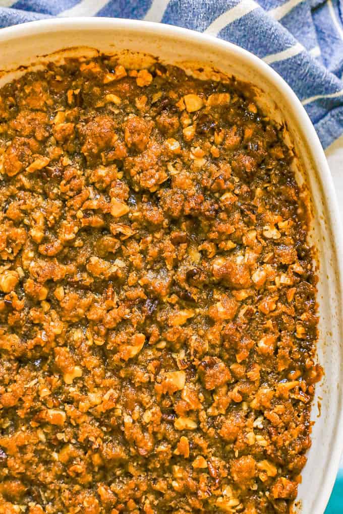 A white baking dish with sweet potato casserole topped with a pecan streusel crust