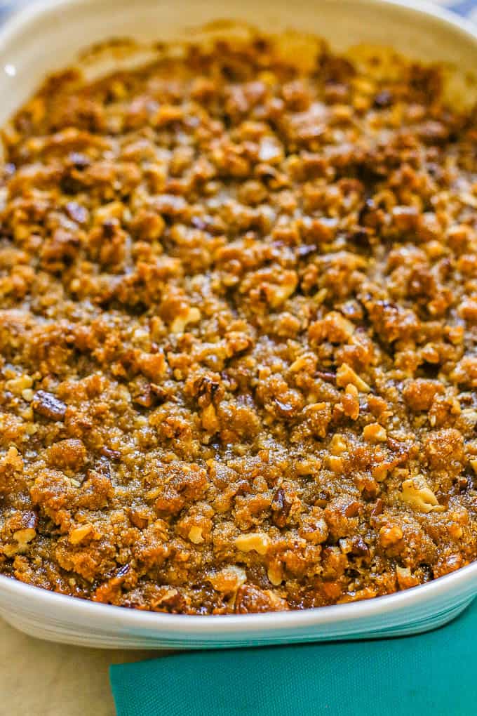 Baked sweet potato casserole with a golden brown pecan streusel topping in a white baking dish