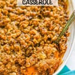 A silver serving spoon scooping out sweet potato casserole with a pecan streusel topping from a white baking dish with a text overlay on the photo