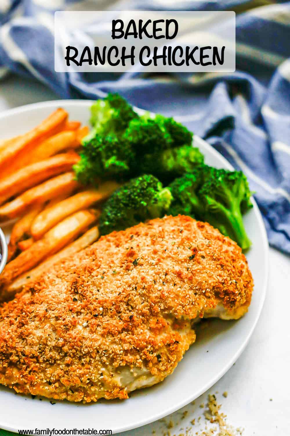 Close up of a white dinner plate with baked Ranch chicken, steamed broccoli and oven fries with a blue striped kitchen towel in the background and a text overlay on the photo