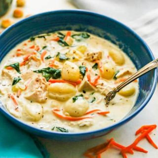 A spoon in a bowl of creamy chicken and gnocchi soup