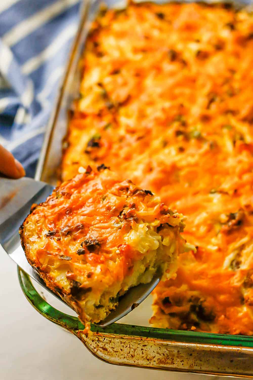 A spatula lifting up a square cut piece of hash brown breakfast casserole