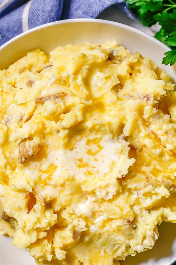 Close up of mashed potatoes with melted butter in a low white bowl