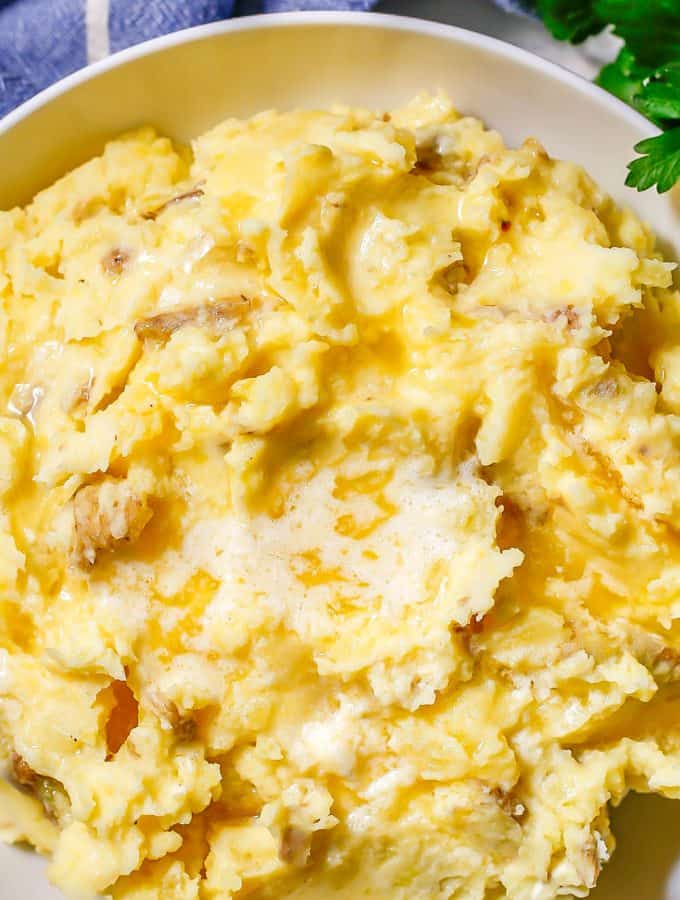 Close up of mashed potatoes with melted butter in a low white bowl