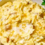 Close up of mashed potatoes with melted butter in a low white bowl with a text overlay on the photo