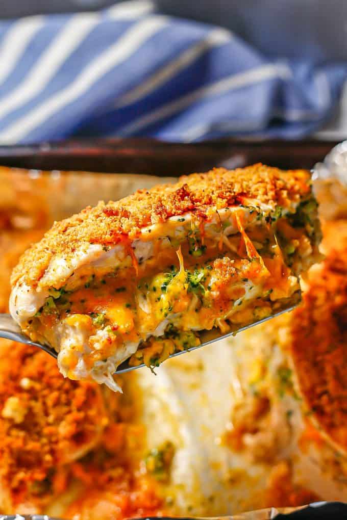 A chicken breast stuffed with broccoli and cheese being lifted from a baking sheet by a spatula