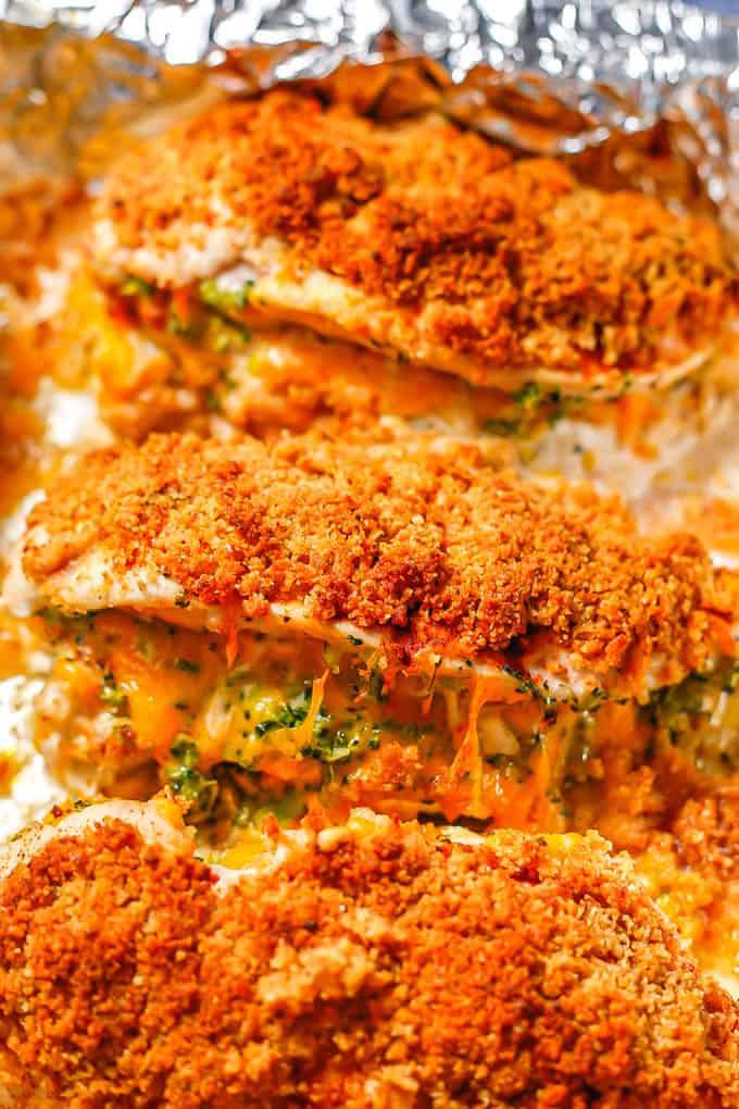 Crunchy baked chicken breasts stuffed with broccoli and cheese on a foil lined baking sheet after cooking.