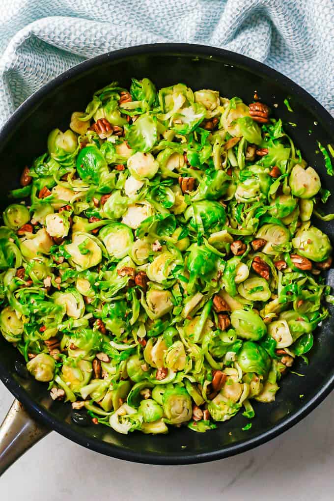 Sautéed shredded Brussels sprouts with pecans in a large skillet