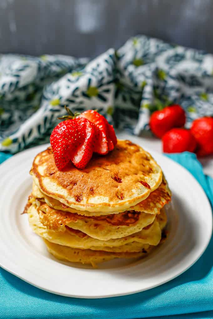 A stack of fluffy cottage cheese pancakes with a sliced strawberry on top.