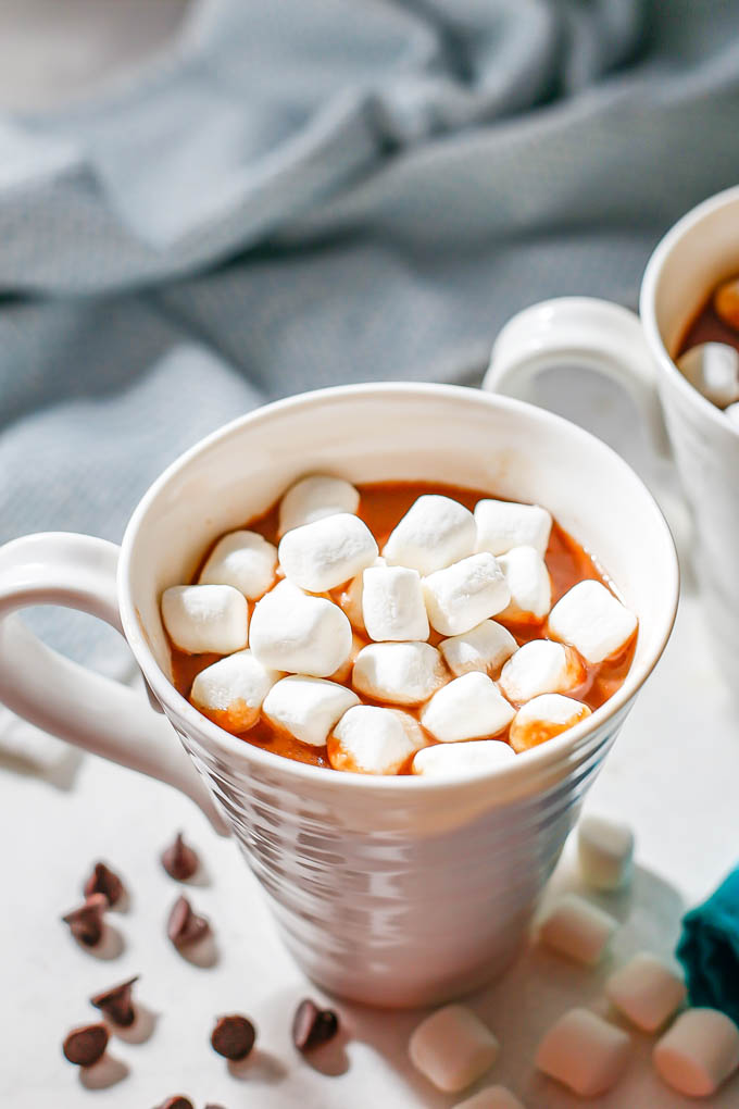 Crock pot hot chocolate in white mugs with mini marshmallows on top