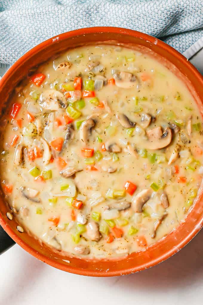 Sautéed veggies in a gravy mixture in a large copper skillet.