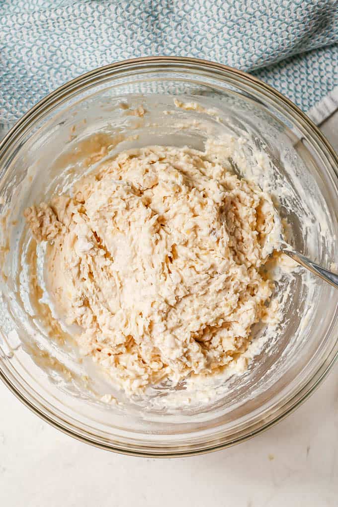 Dough for dumplings being stirred together in a large glass bowl.