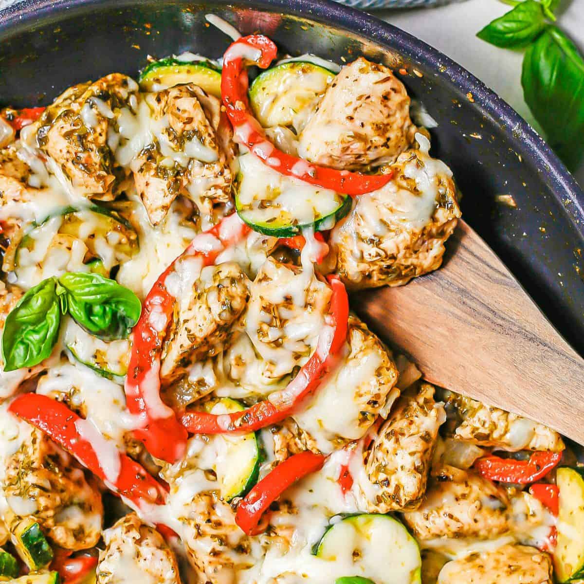 Italian chicken skillet with pesto and veggies and cheese on top.