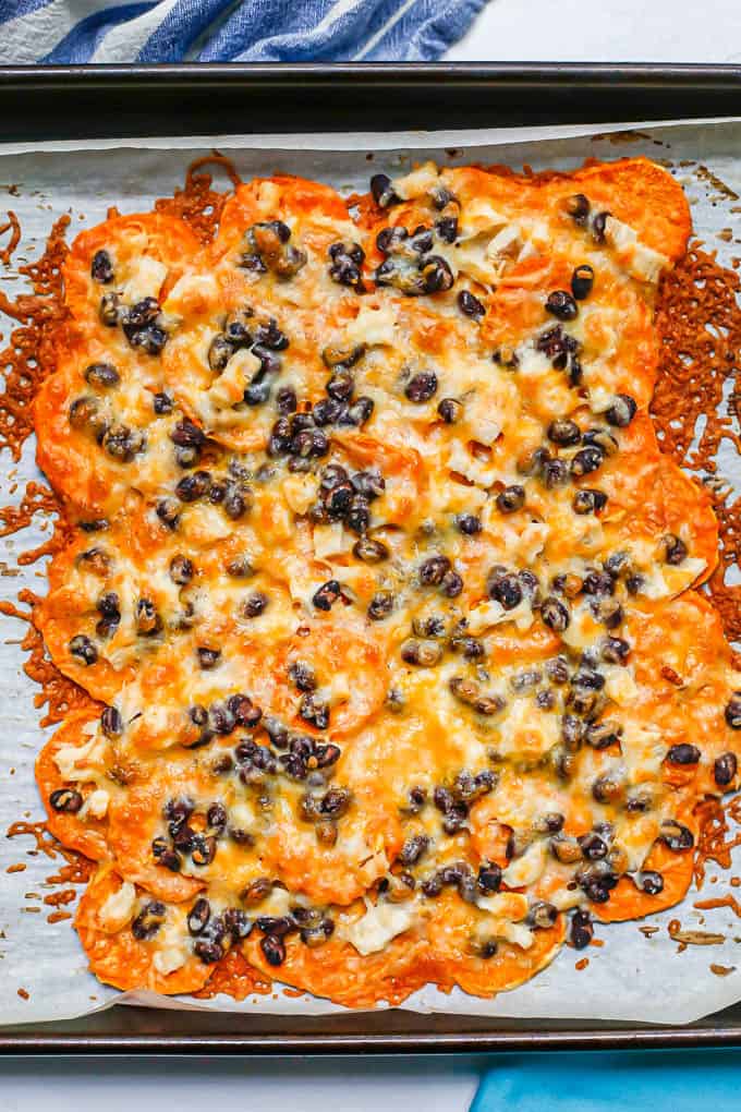 Sweet potato nachos with chicken, black beans and cheese on a baking sheet after being baked.