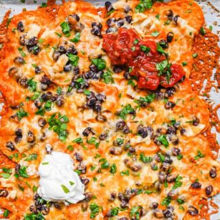 Nachos with a base of sweet potatoes topped with beans, chicken, cheese and toppings.