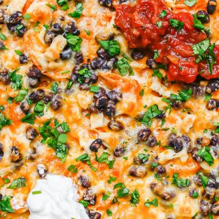 Loaded cheesy sweet potato nachos topped with salsa and sour cream.