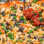 A sheet pan filled with sweet potato nachos topped with black beans, cheese, cilantro, salsa and sour cream with a text overlay on the photo.