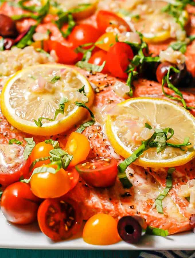 Large roasted salmon filets topped with lemon slices, assorted colored tomatoes, olives, basil and a shallot dressing