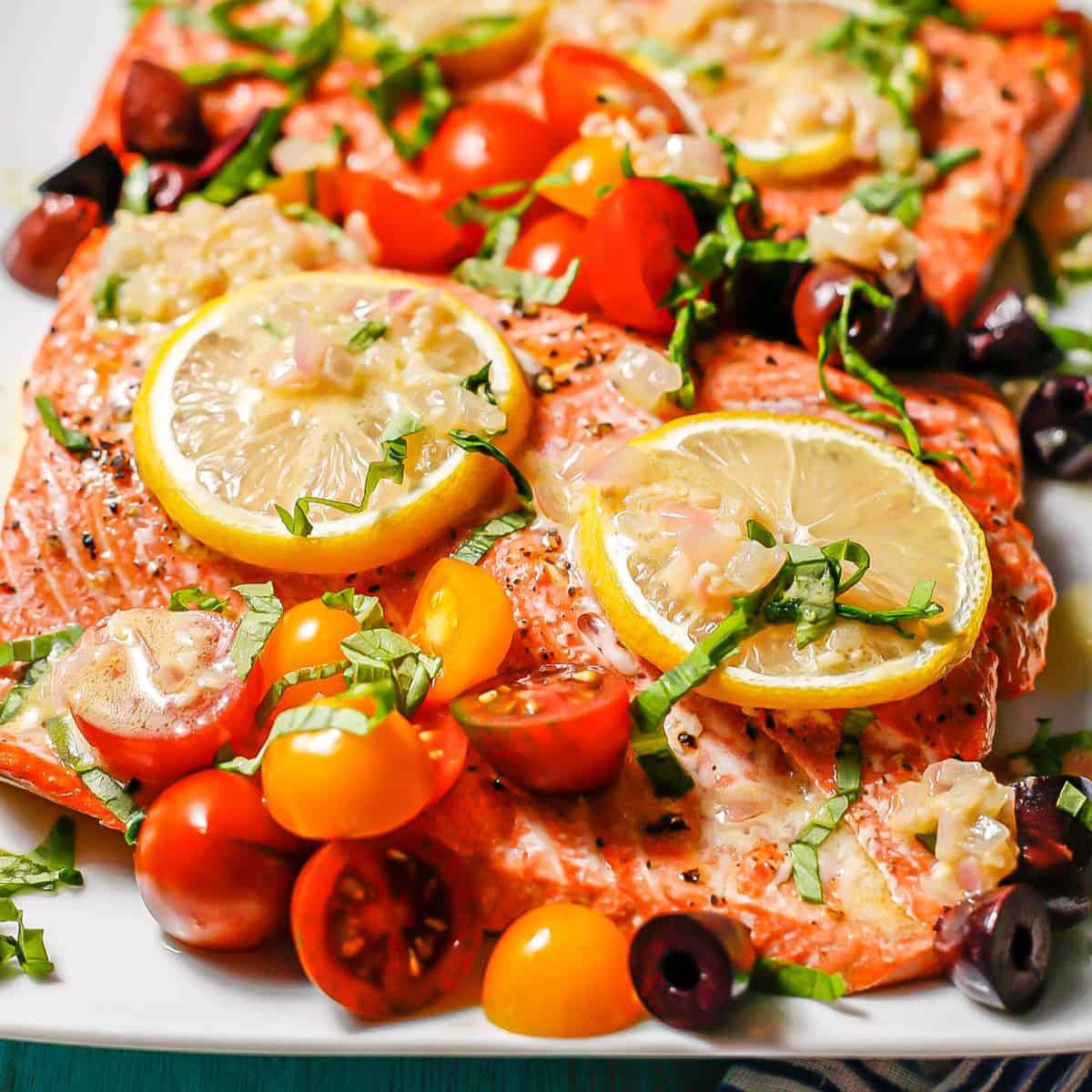 Large roasted salmon filets topped with lemon slices, assorted colored tomatoes, olives, basil and a shallot dressing