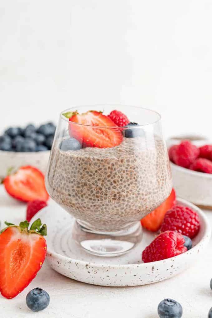 A clear glass filled with chia seed pudding and topped with berries.