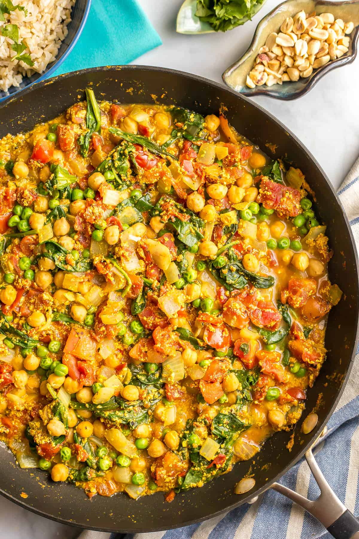 Close up of a veggie filled curry in a large dark skillet.