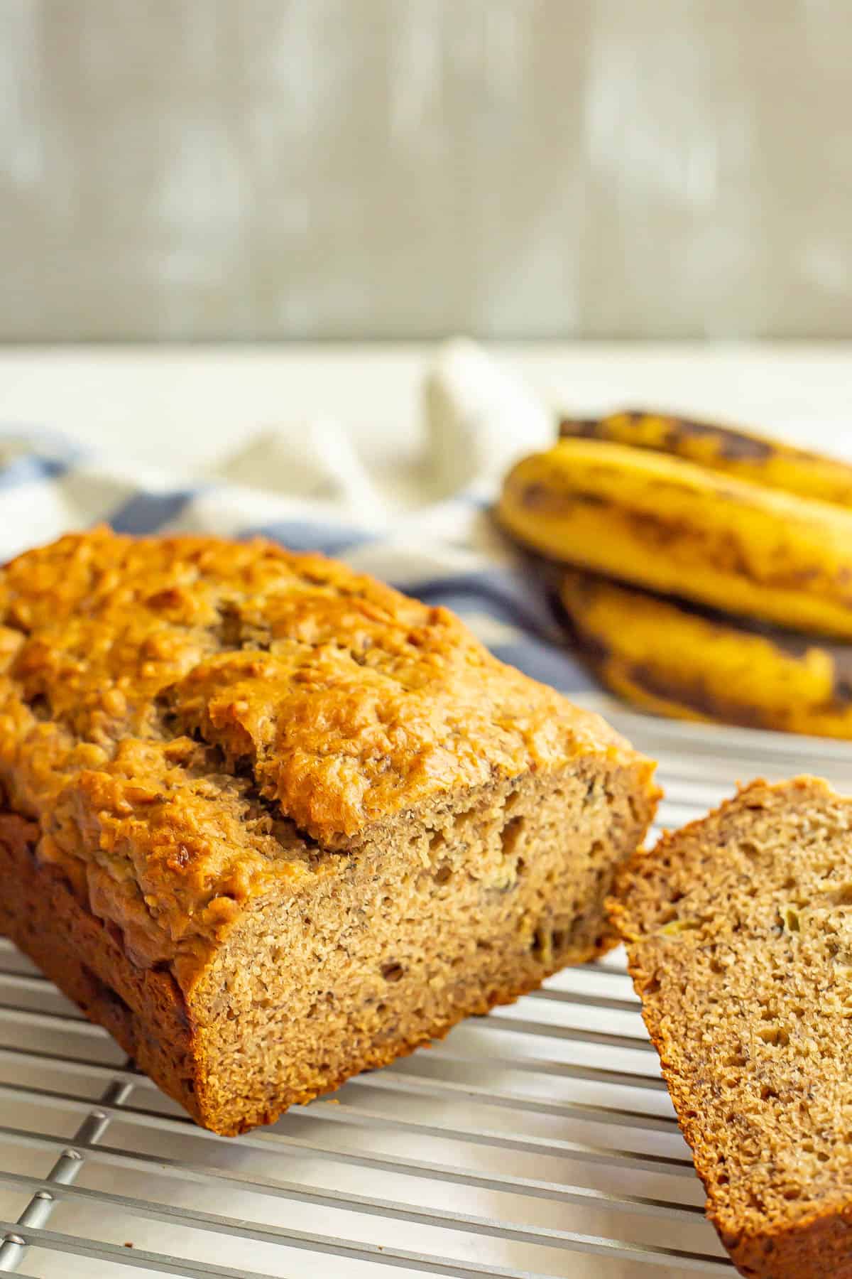 Banana bread on a cooling rack with a couple of slices to the side.