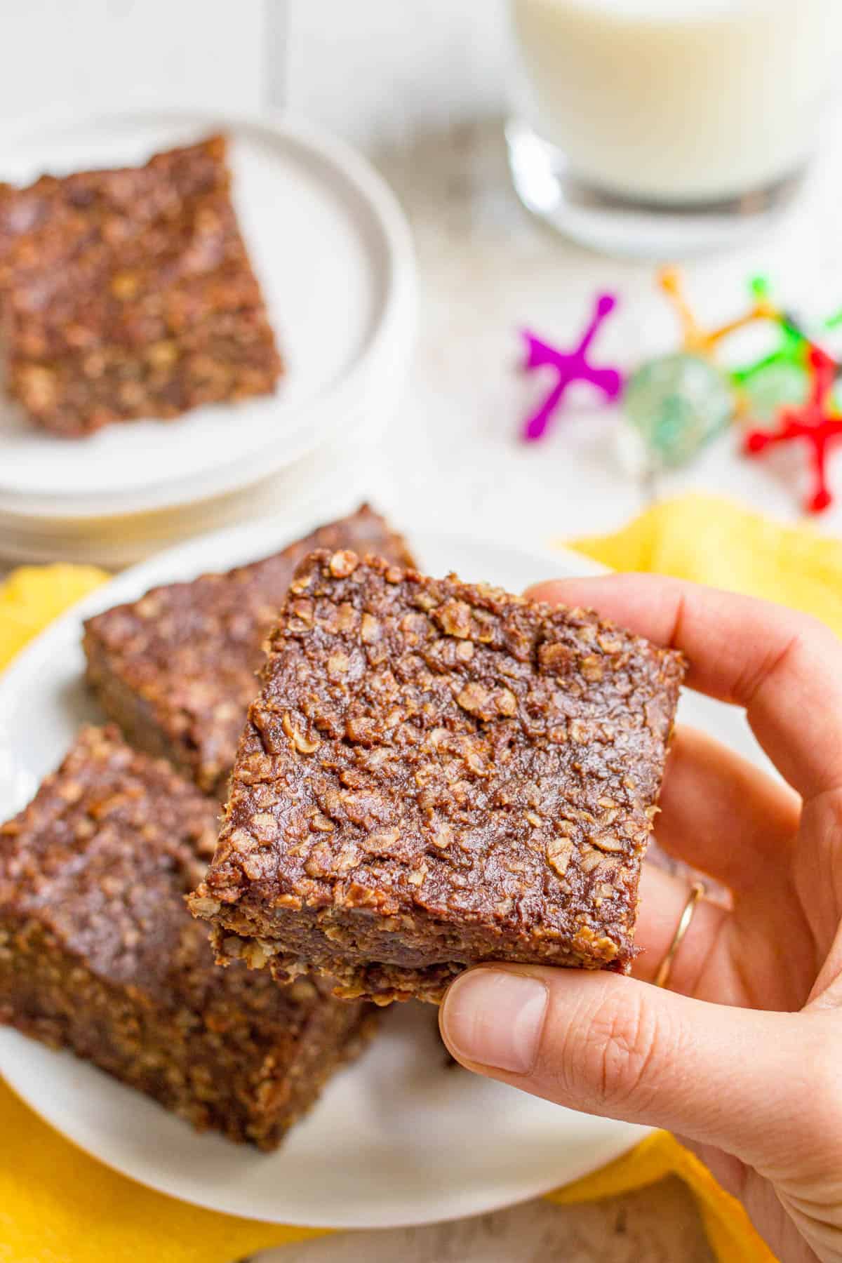 A hand picking up a chocolate peanut butter no bake cookie bar from a plate.