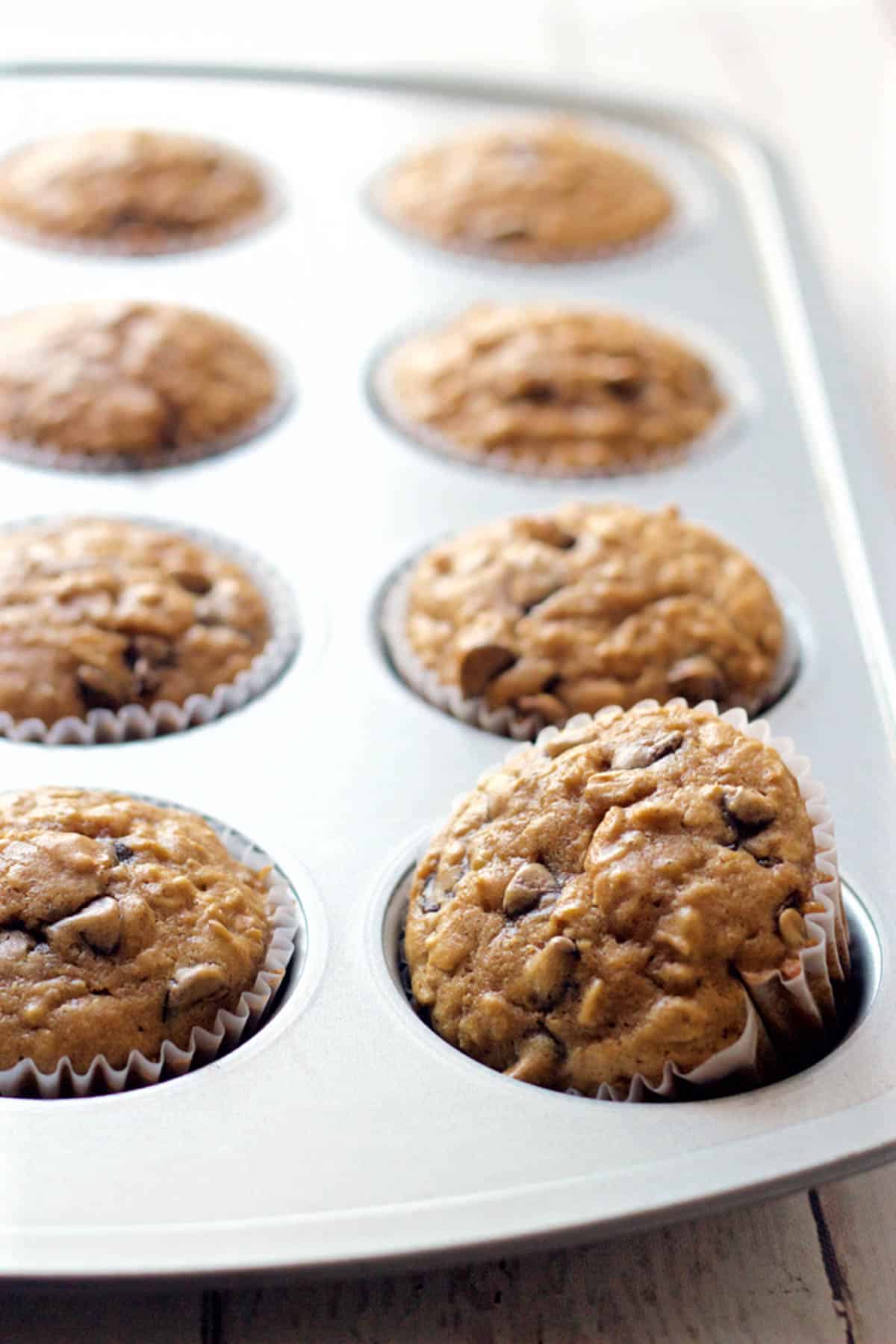 A healthy chocolate chip muffin tilted on its side in a muffin tin.