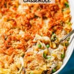 A scoop being taken out of a baked tuna noodle casserole with a crunchy browned breadcrumb topping and a text overlay on the photo.