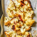 Roasted cauliflower on a baking sheet topped with grated Parmesan cheese and a text overlay on the photo.