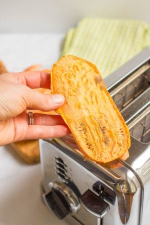A hand holding up a piece of sweet potato toast after it's toasted.