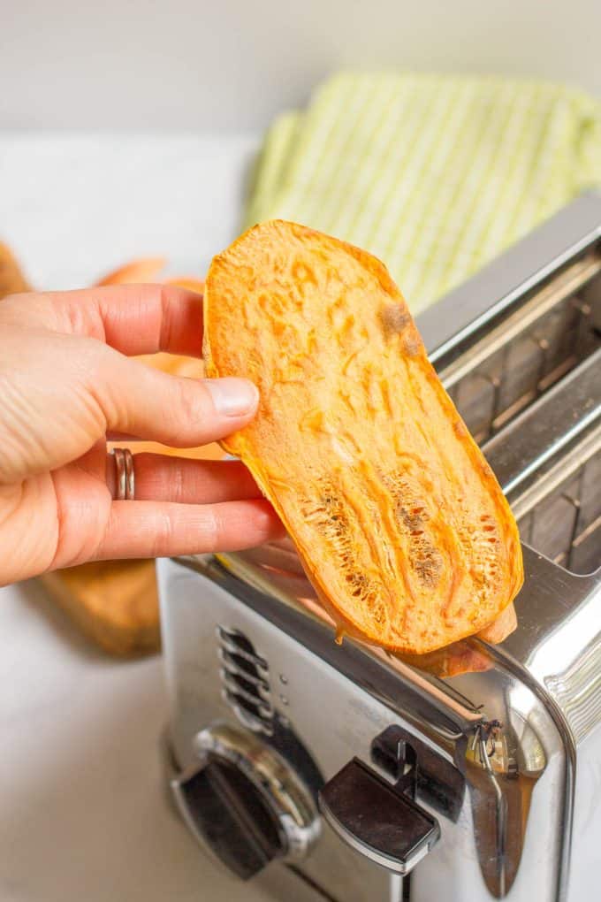 A hand holding up a piece of sweet potato toast after it's toasted.