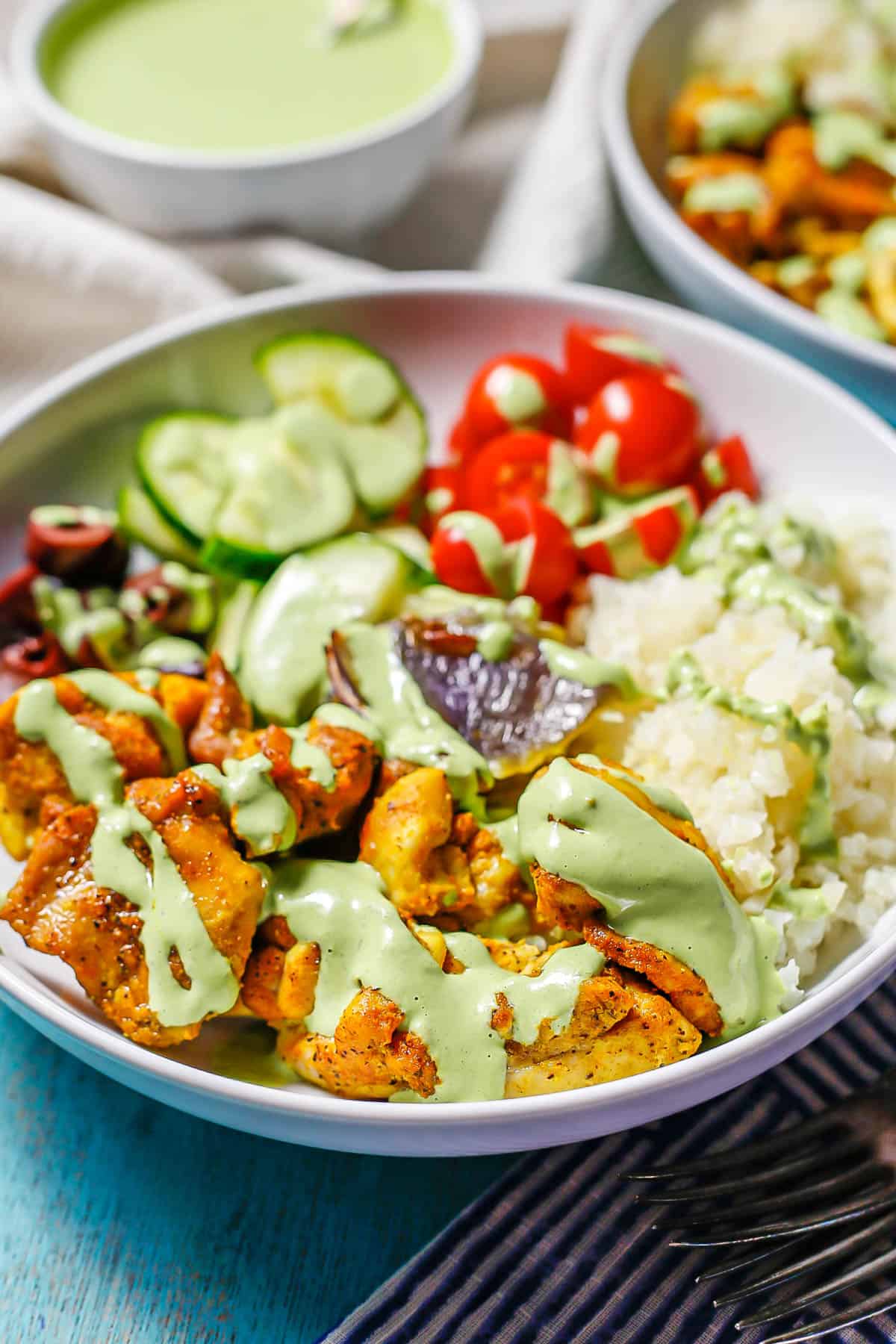 Side view of a cauliflower rice bowl topped with a tahini herb dressing.