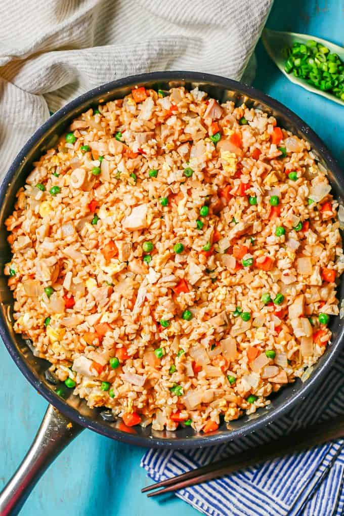 Chicken fried rice with peas and carrots in a large dark skillet.