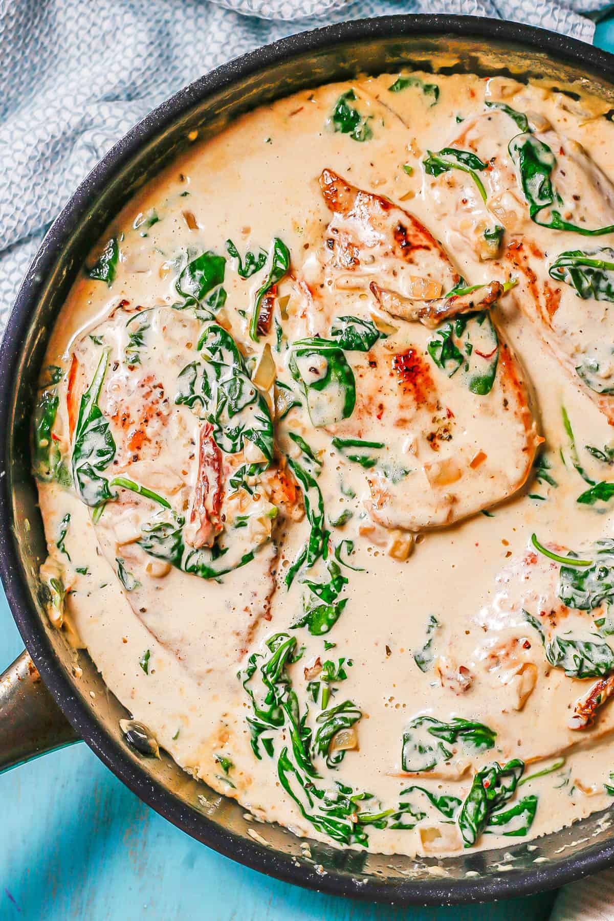 Creamy Tuscan chicken with spinach and sun dried tomatoes in a large dark skillet.