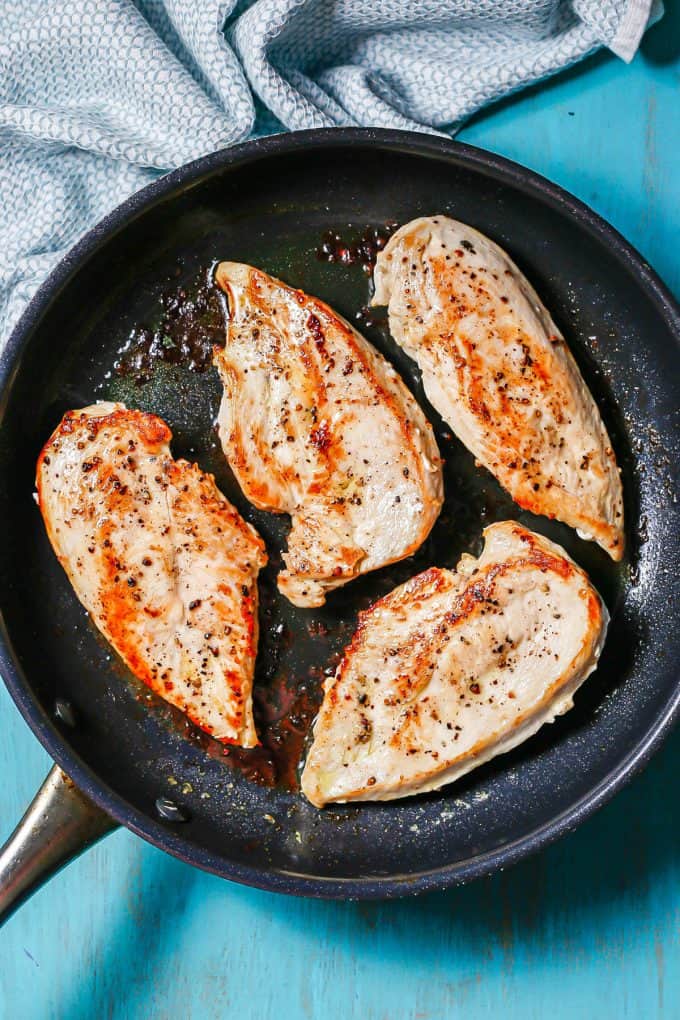 Seared chicken cutlets in a large dark skillet.