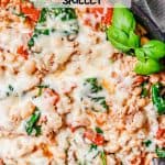 Close up of melted mozzarella cheese on top of a mixture of ground chicken, white beans, spinach and tomatoes in a large dark pan with a text overlay on the photo.