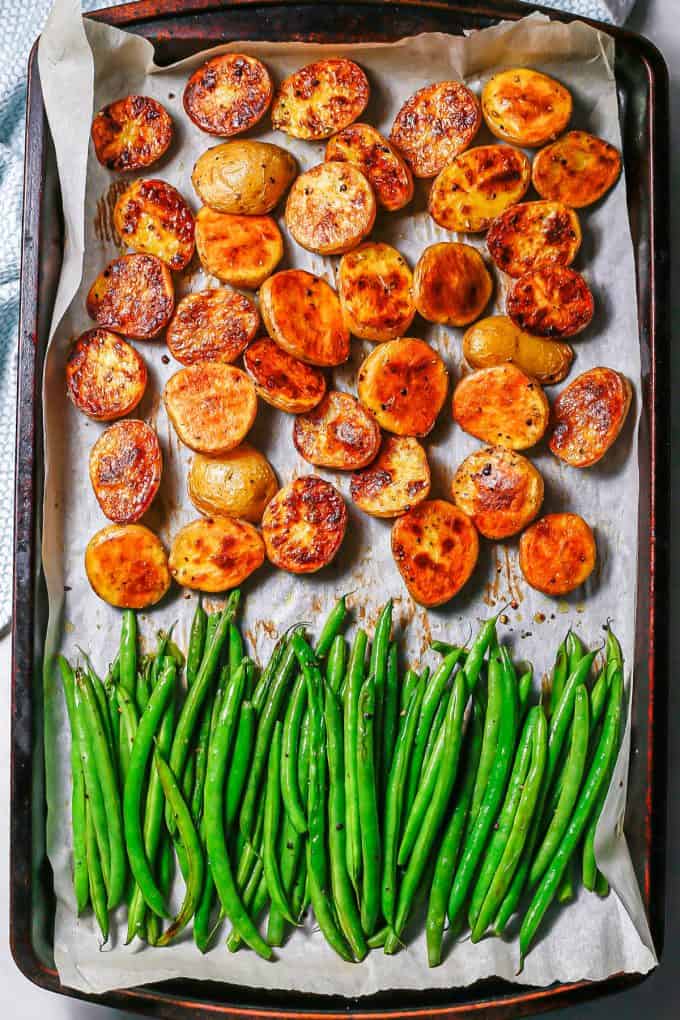 A parchment paper lined sheet pan with roasted potatoes and haricot verts.