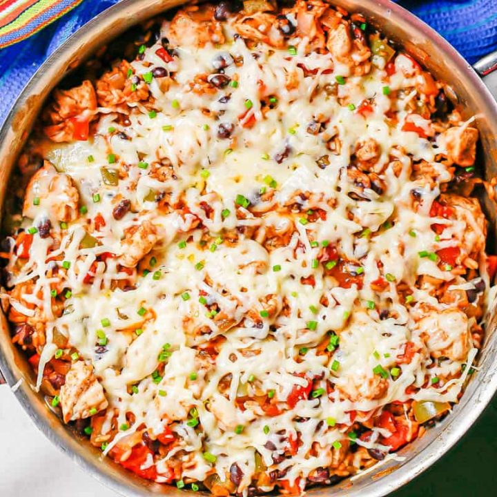 A cheesy chicken and rice skillet with black beans, tomatoes and peppers.
