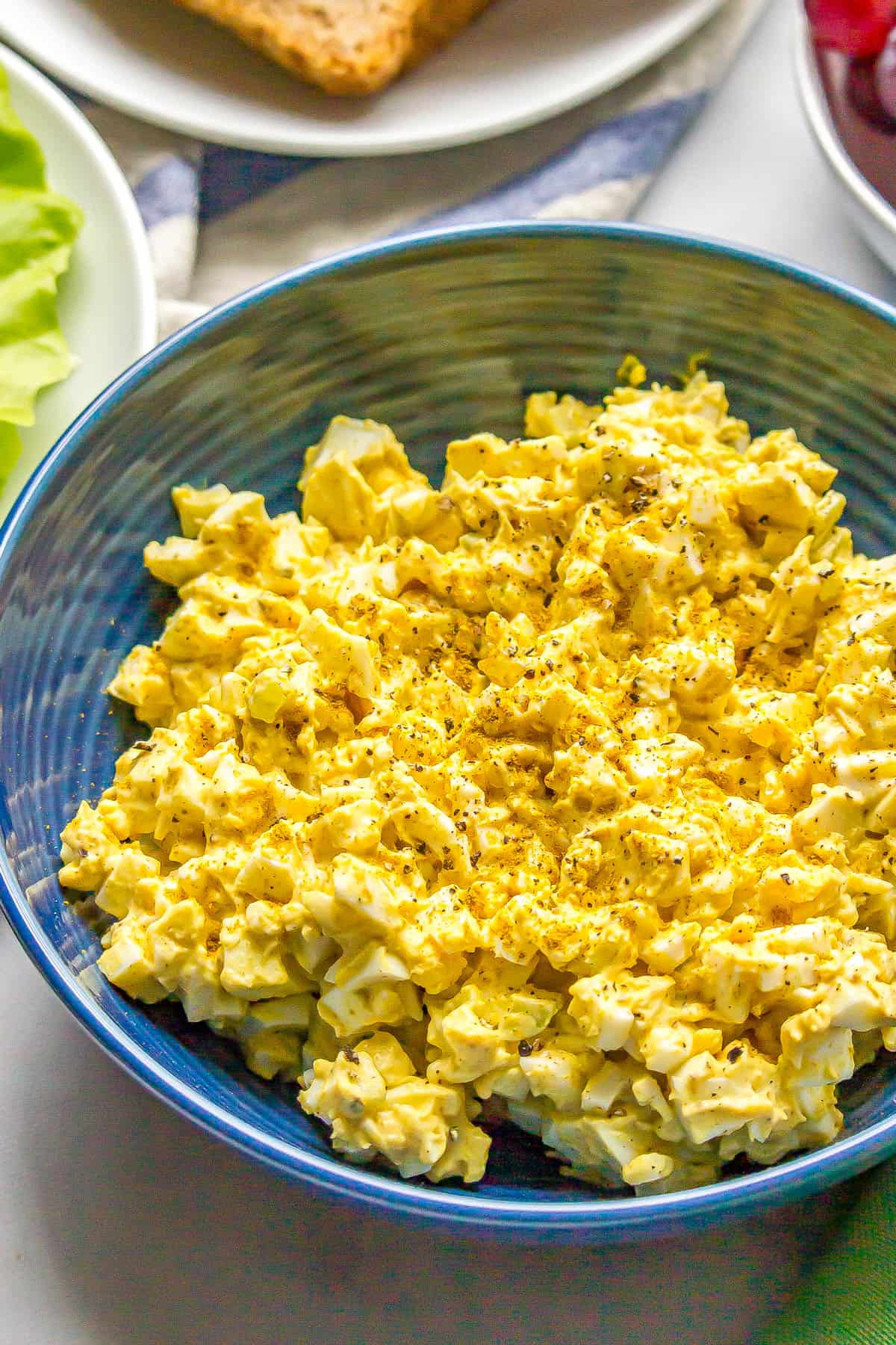 Close up of curried egg salad in a blue bowl.