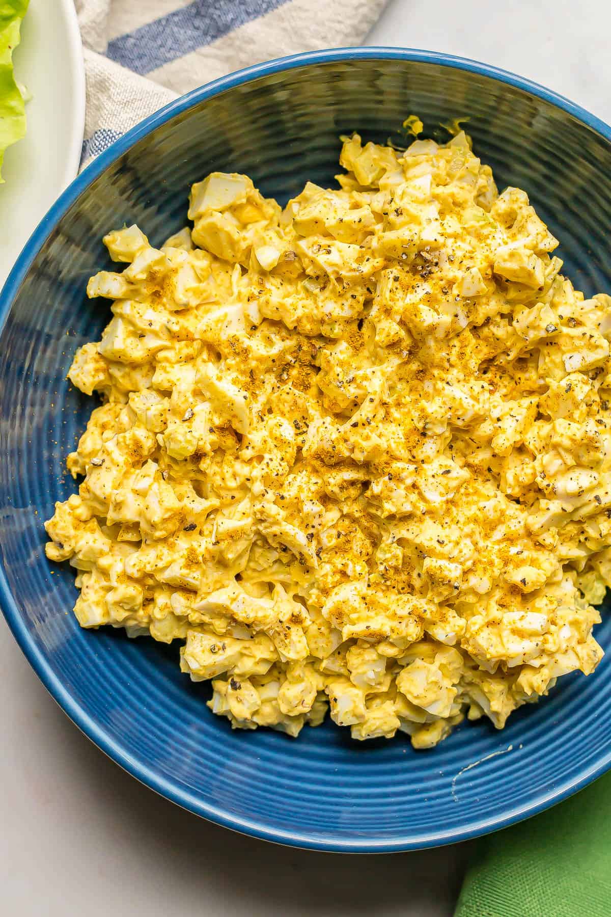 Egg salad with curry powder in a blue bowl.