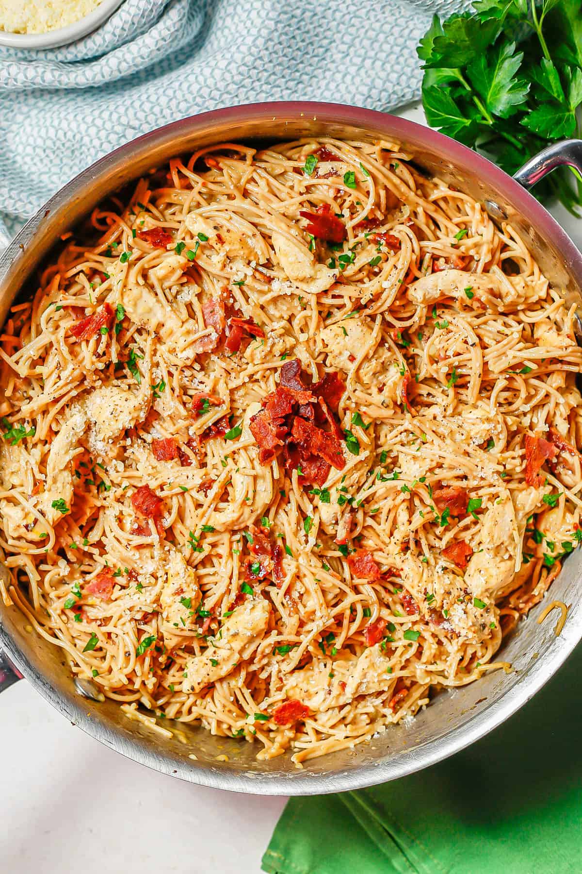 Chicken carbonara in a large deep skillet topped with extra bacon and chopped fresh parsley.