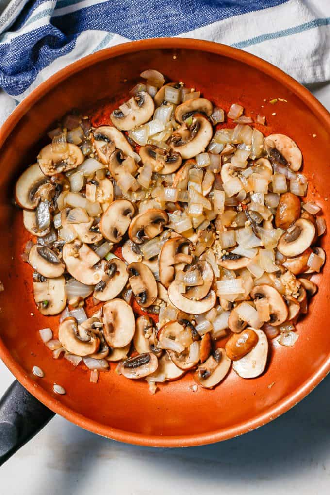 Sautéed onion and mushrooms in a large copper skillet.