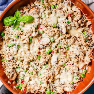 Close up of a cooked skillet of ground chicken and mushrooms with peas and mozzarella cheese.