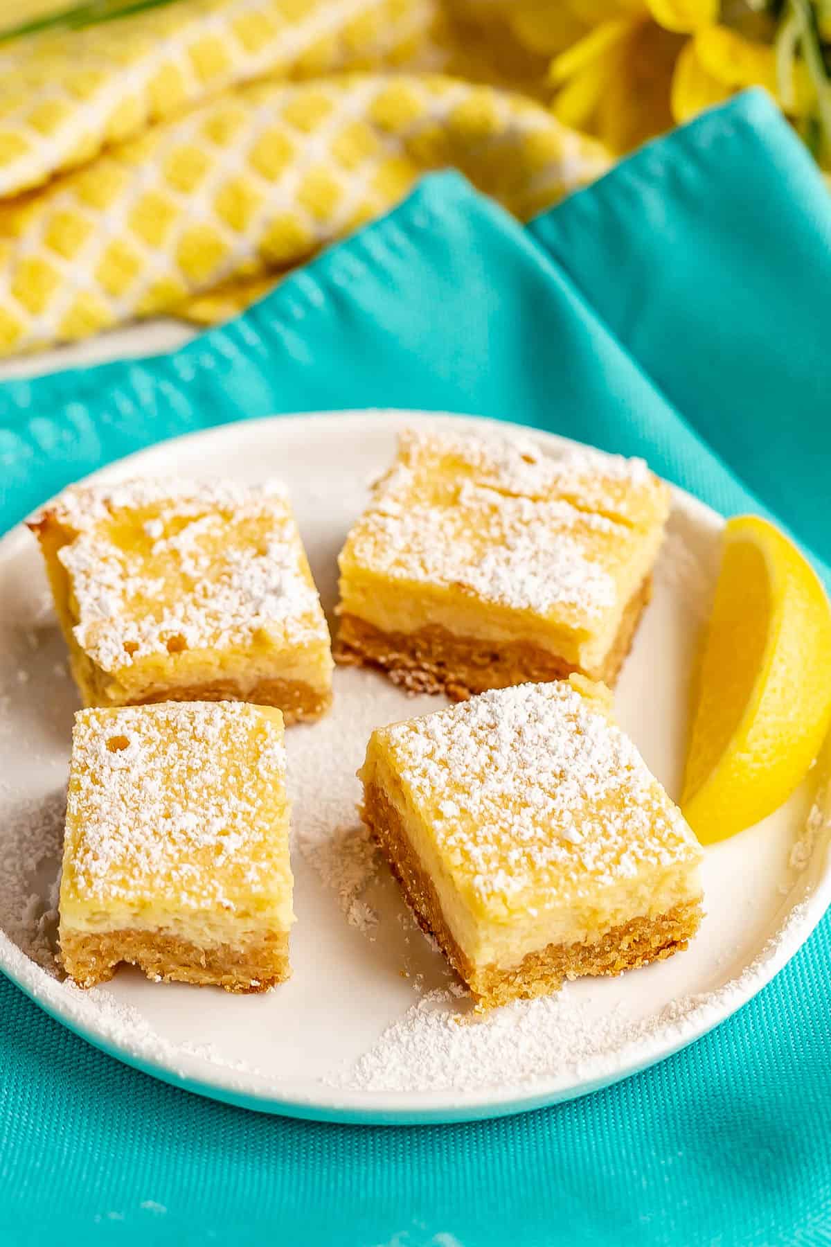 A small white plate with healthy lemon bars topped with powdered sugar.